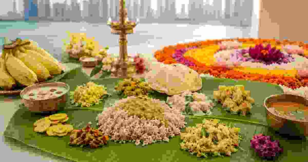 Traditional Onam sadhya served on a banana leaf with pookalam and brass lamp in Dubai